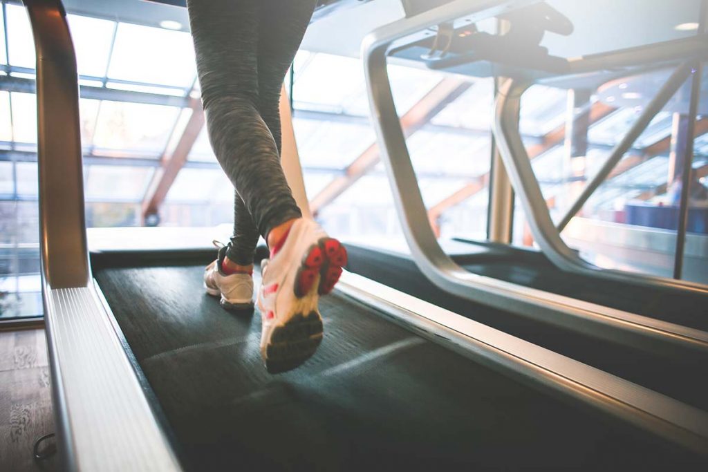Person running on a treadmill in a modern gym setting.