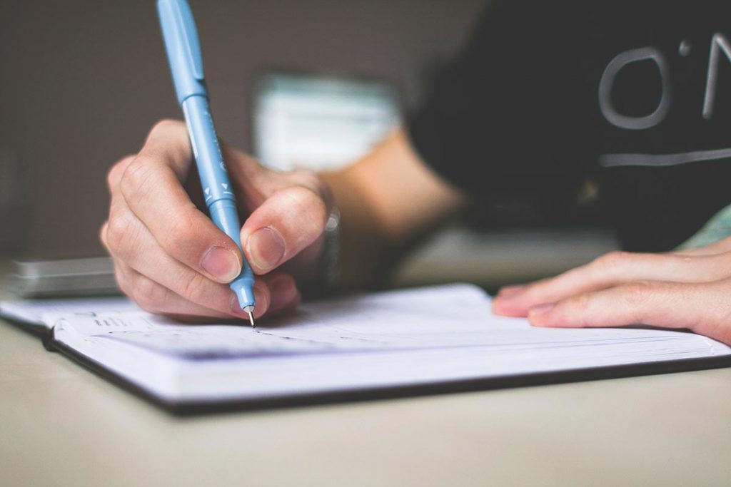 Person signing a contract for bin hire services at a desk.